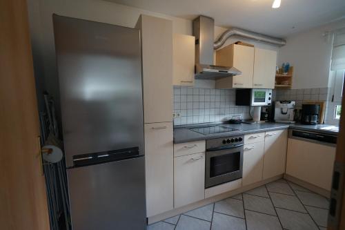 a kitchen with white cabinets and a stainless steel refrigerator at Ferienwohnung mit gemütlicher Terrasse im Nordschwarzwald in Oberreichenbach