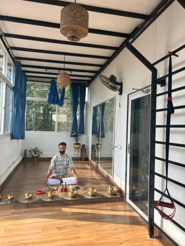 a man sitting on the floor of a room with gold bowls at Prana Healing House in Pune