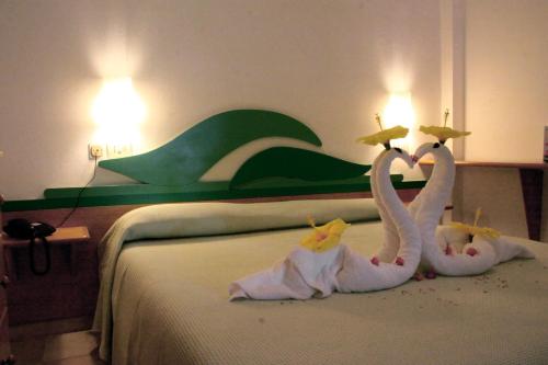 two swans made out of towels sitting on a bed at Hotel Villaggio Cala Di Volpe in Capo Vaticano