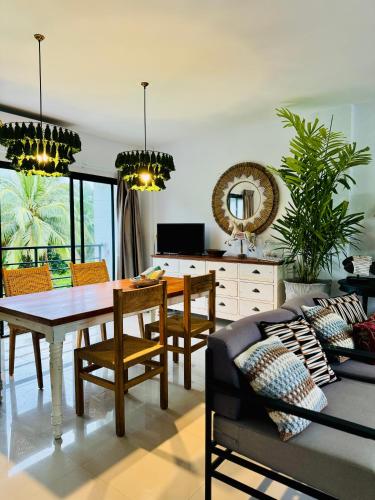 a living room with a dining room table and a couch at Villa Think Of Home in Khao Lak