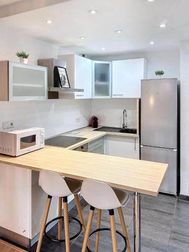 une cuisine avec des armoires blanches et un comptoir en bois dans l'établissement Appartement avec grande terrasse, à Saint-Laurent-du-Var