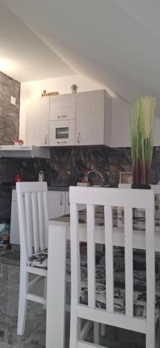 a kitchen with white cabinets and two white chairs at APARTMENTS IVANOViC CENTER CITY in Bajina Bašta