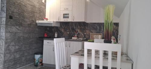 a kitchen with white cabinets and a table and chairs at APARTMENTS IVANOViC CENTER CITY in Bajina Bašta