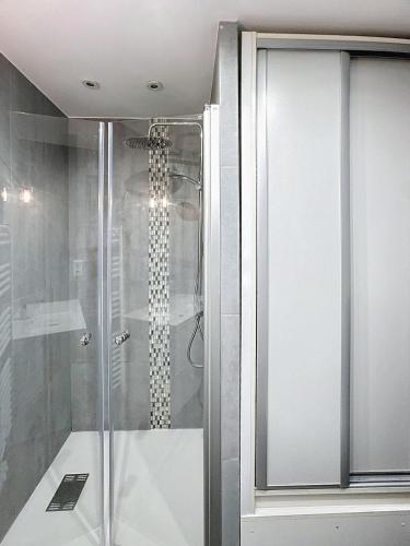 une douche avec une porte vitrée dans une salle de bain dans l'établissement Appartement avec grande terrasse, à Saint-Laurent-du-Var