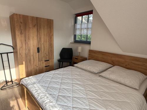 a bedroom with a bed and a window and a chair at Ferienwohnung Seeigel in Prerow