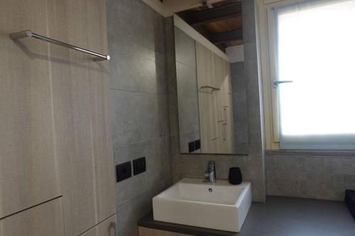 łazienka z białą umywalką i lustrem w obiekcie Loft Cùntra Maestra w Asti
