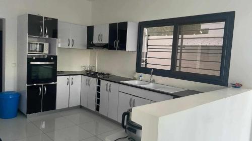 a kitchen with black and white appliances and a window at Villa Vielet Lalovina in Mahajanga