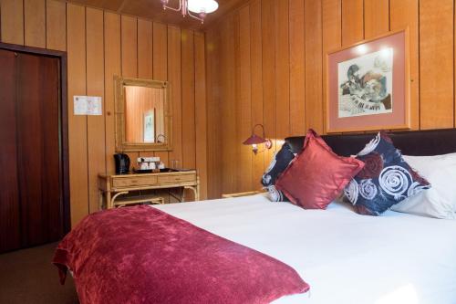 a bedroom with a large white bed with red pillows at Kings Lodge Hotel in Hogsback
