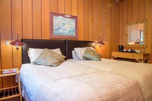 two beds in a room with wood panel walls at Kings Lodge Hotel in Hogsback