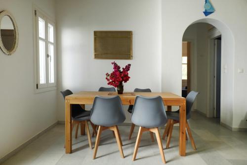 a dining room table with chairs and a vase of flowers at casa maia in Kampos Paros