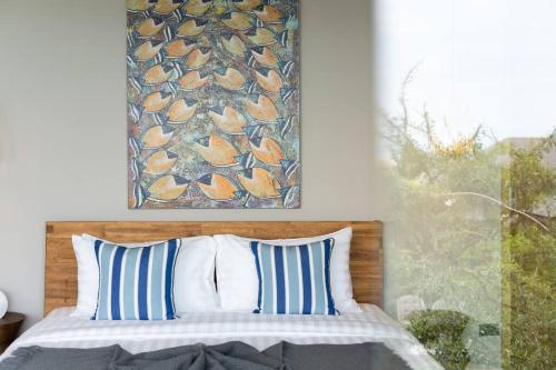 a bed with blue and white pillows and a picture on the wall at 班塔莱海滨之家1号 in Koh Samui