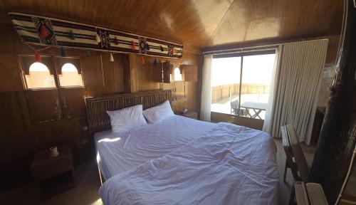 a bedroom with a bed with a blue comforter and a window at AArabian Sand Camp Empty Quater Salalah Oman in Fasad