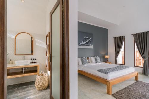 a bedroom with a bed and a sink and a mirror at Villa Skyler Seminyak in Seminyak