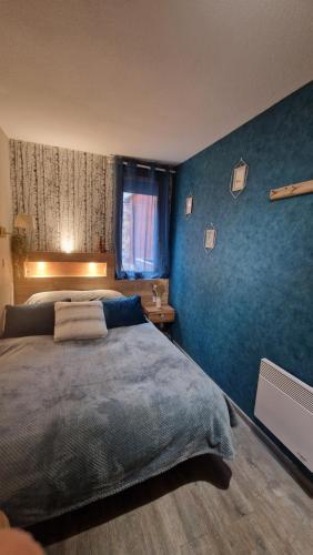 une chambre avec un grand lit et un mur bleu dans l'établissement Risoul - Apt 10 pers au pied des pistes, à Risoul