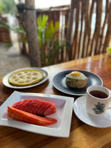 a table with two plates of food and a cup of coffee at Sentigi Homestay Gili Gede in Gili Gede