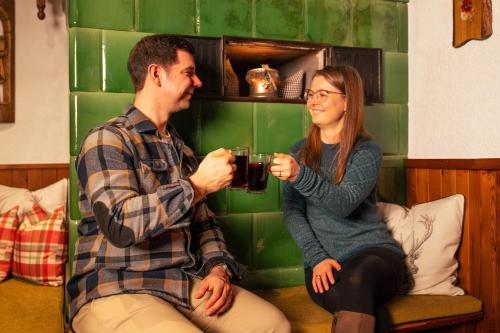 a man and a woman sitting on a couch drinking at Naturparkhotel Schwarzwaldhaus in Bernau im Schwarzwald