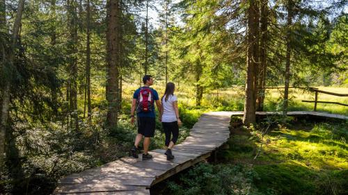 a man and a woman walking on a wooden bridge at Naturparkhotel Schwarzwaldhaus in Bernau im Schwarzwald