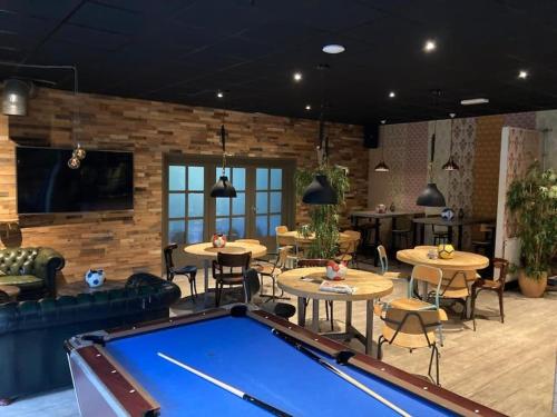 a pool table in a room with tables and chairs at Sfeervol Tiny House in het Bos in Diessen
