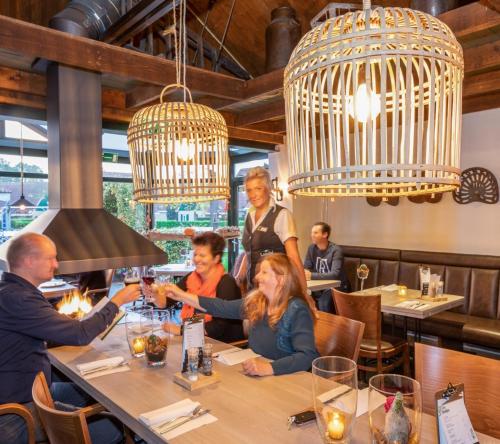 a group of people sitting at a table in a restaurant at Sfeervol Tiny House in het Bos in Diessen