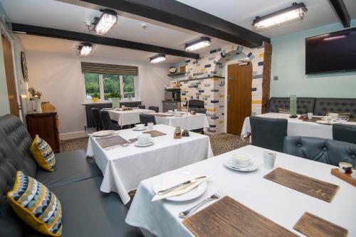 a dining room with white tables and chairs at Bridleways Guesthouse & Holiday Homes in Mansfield