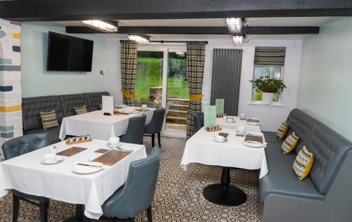 a restaurant with white tables and blue chairs at Bridleways Guesthouse & Holiday Homes in Mansfield