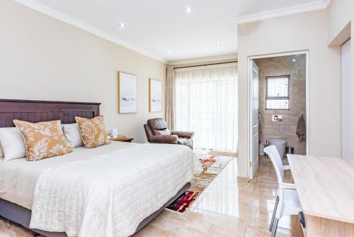 a bedroom with a bed and a table and a chair at 150 Jacaranda Guesthouse in Midrand