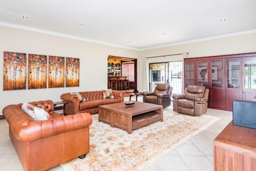 a living room with leather furniture and a table at 150 Jacaranda Guesthouse in Midrand