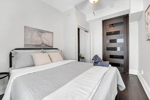 a white bedroom with a large bed and a chair at Luxury 2BR Home Near DT GO Hospitals Waterfalls in Hamilton