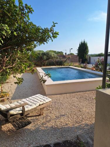 une piscine avec un banc devant dans l'établissement Les Cigales de Saint Quentin la Poterie, à Saint-Quentin-la-Poterie