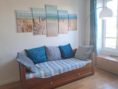 a couch in a room with four paintings on the wall at Studio Pont de Sèvres bien situé in Sèvres