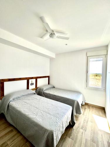 two beds in a room with a ceiling fan at Casa Rural MaciasDehesa in Mérida