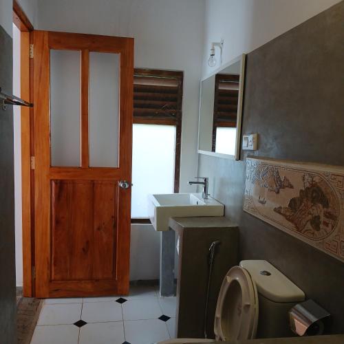 a bathroom with a toilet and a sink and a door at La-Vira Beach Villa in Hikkaduwa