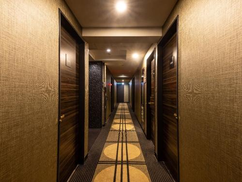 a hallway with wooden doors and a long hallway with a corridorngthngthngthngth at APA Hotel Tokyo Kudanshita in Tokyo