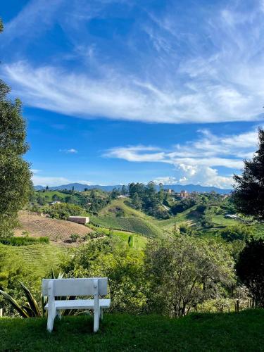 a white bench sitting on top of a green hill at Hermosa casa finca en Marinilla in Marinilla