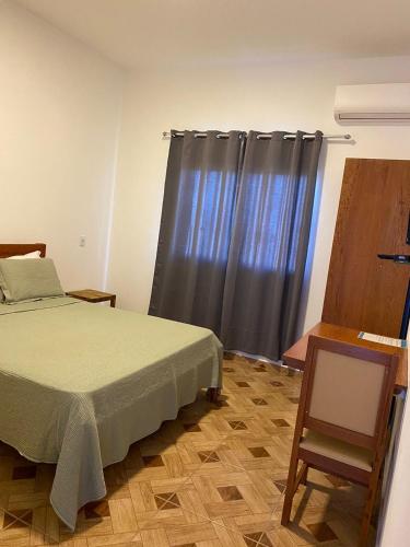 ein Schlafzimmer mit einem Bett und einem grauen Vorhang in der Unterkunft Aguazul Hotel in Augusto de Lima