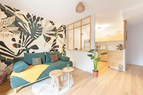 un salon avec un canapé vert et une cuisine dans l'établissement Le Tropical Bali, Appt T2, proche métro et centre ville, à Toulouse