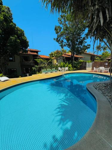 a large swimming pool with blue water in a yard at Pousada Coisa e Tao in Arraial d'Ajuda