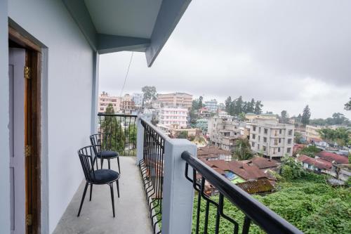 a balcony with two chairs and a view of a city at Silvermist BnB in Shillong