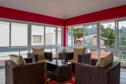 a living room with chairs and a table and windows at Green Premium Villa Ooty by Lexstays in Ooty