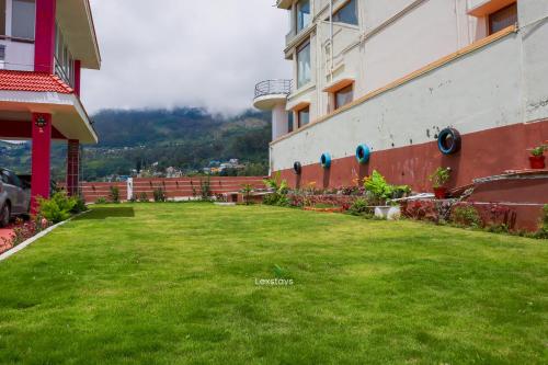a green lawn in front of a building at Green Premium Villa Ooty by Lexstays in Ooty