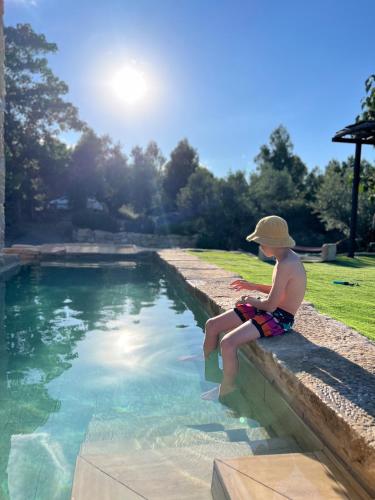 a young boy sitting on a ledge next to a swimming pool at Serra de Martines in Batea