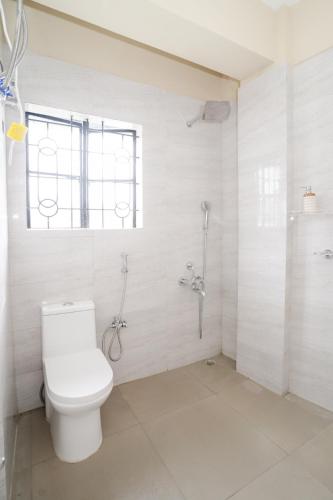 a white bathroom with a toilet and a shower at Silvermist BnB in Shillong