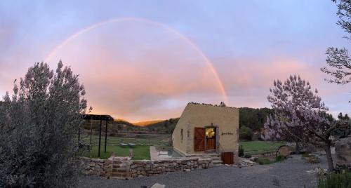 a rainbow over a house with a building at Serra de Martines in Batea
