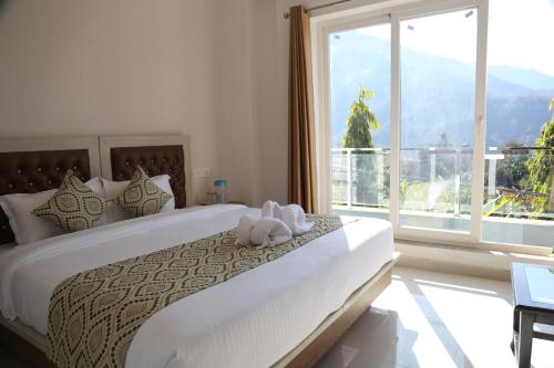 una camera da letto con un letto grande con una grande finestra di Hotel yog tapovan MOUNTAIN VIEW ROOM a Rishikesh