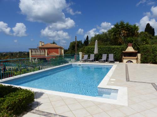a swimming pool with two chairs and a house at Villa Helios, Kaligata - First floor apartment in Metaxáta