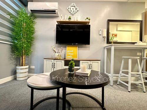 a living room with a table and a tv on a wall at Jimenez Staycation Unit 406 Quirino west tower The Residence at Commonwealth by Century in Manila