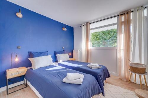 a blue bedroom with two beds and a window at Fridhome Parking Wifi Fibre 2MIN Tram in Bruges