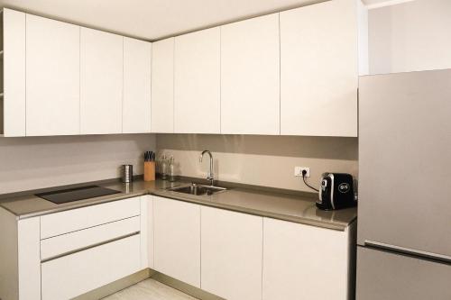 a white kitchen with a sink and a refrigerator at Udine Center Apartment in Udine