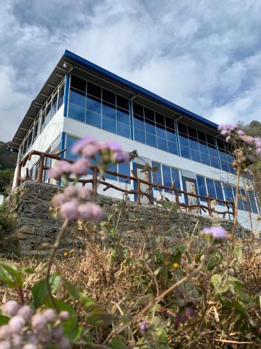 a building with windows on top of a field of flowers at sanjivani buti organic krisi farm & resort in Nagarkot