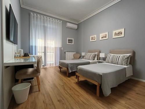 una camera da letto con due letti, un tavolo e un divano di Canfora 163 Cutaias apartment a Catania